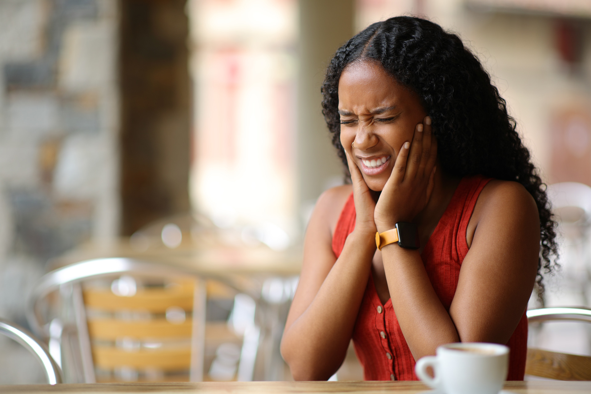 A person in pain from TMJ disorder holding their jaw with both hands.