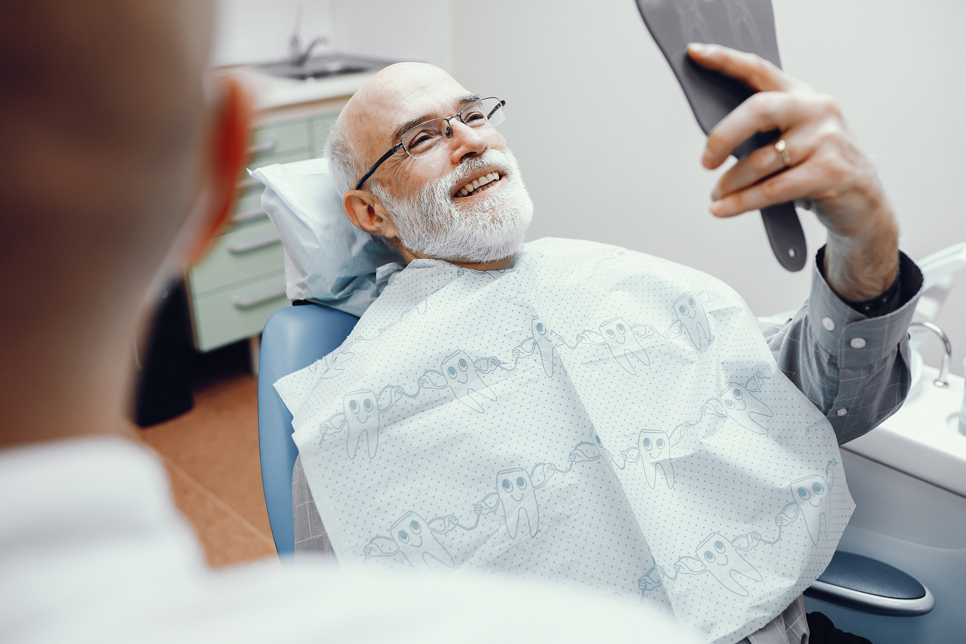 A man in a dental chair holding a toothbrush, preparing for a reconstructive dentistry procedure.