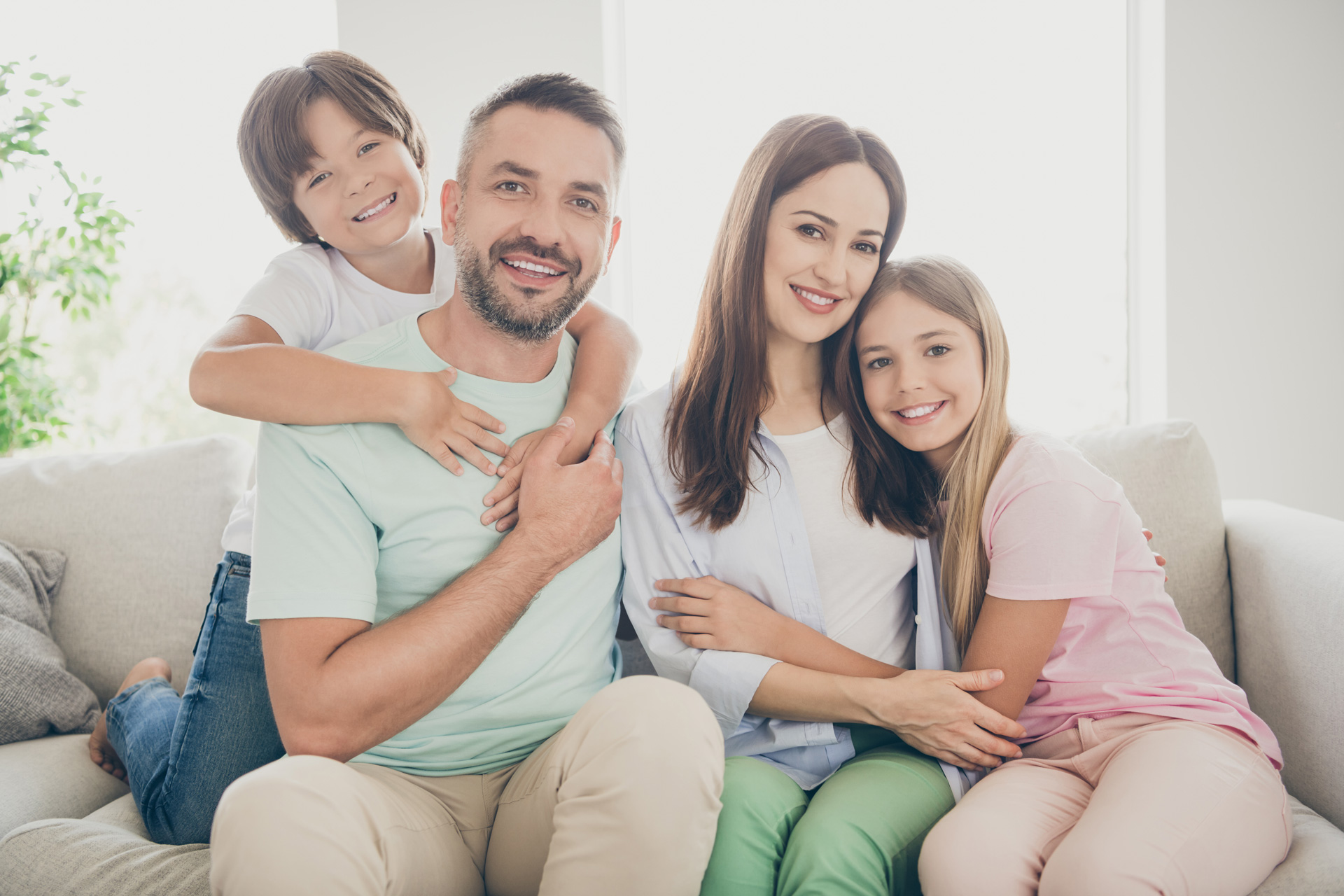 A cheerful family with bright smiles relaxes on a couch.