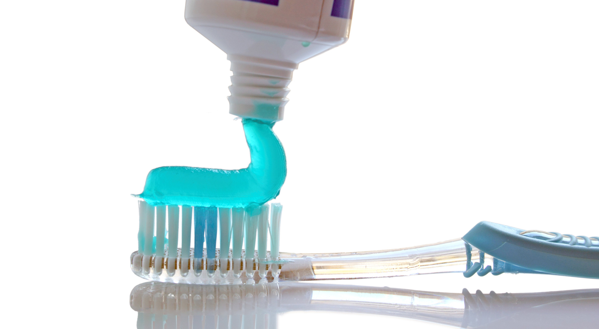 A close-up view of toothpaste being applied to the head of a toothbrush.