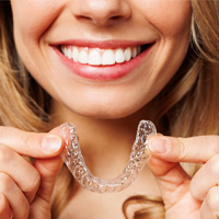 Person smiling, holding Invisalign in both hands.